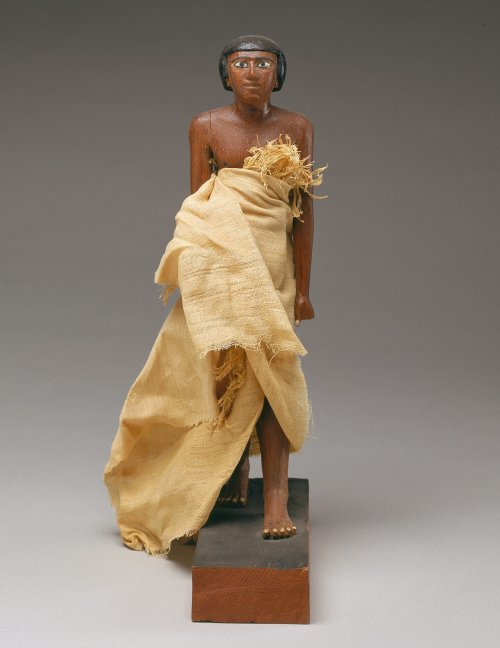 Estátua de Wah encontrada na tumba MMA 1102. 32 cm de altura. Essa manta de linho talvez imite o tipo de saia longa usada por oficiais do Reino Médio. MET. N° 20.3.210